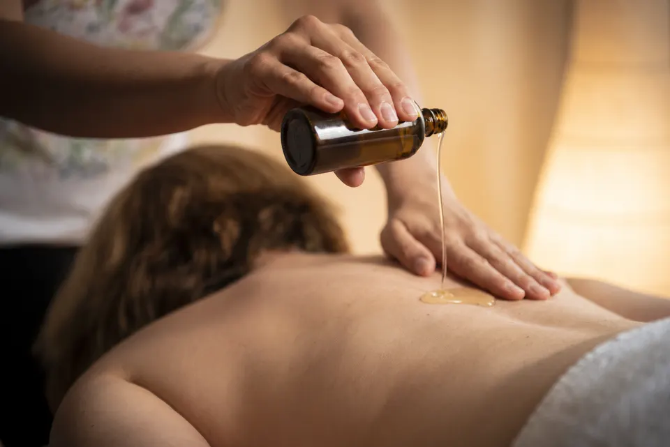 Massageöl wird auf den Rücken getropft